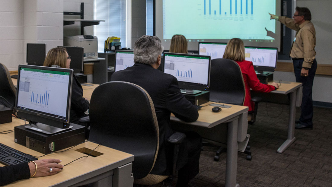 People sitting in a computer lab listening to a lecture