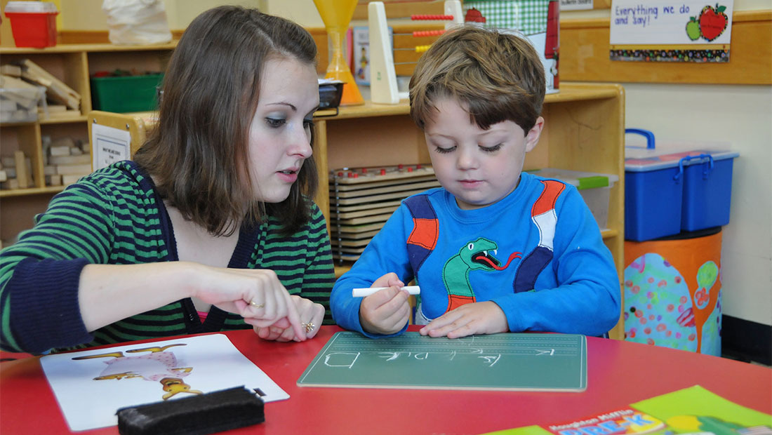 Woman watching a child write