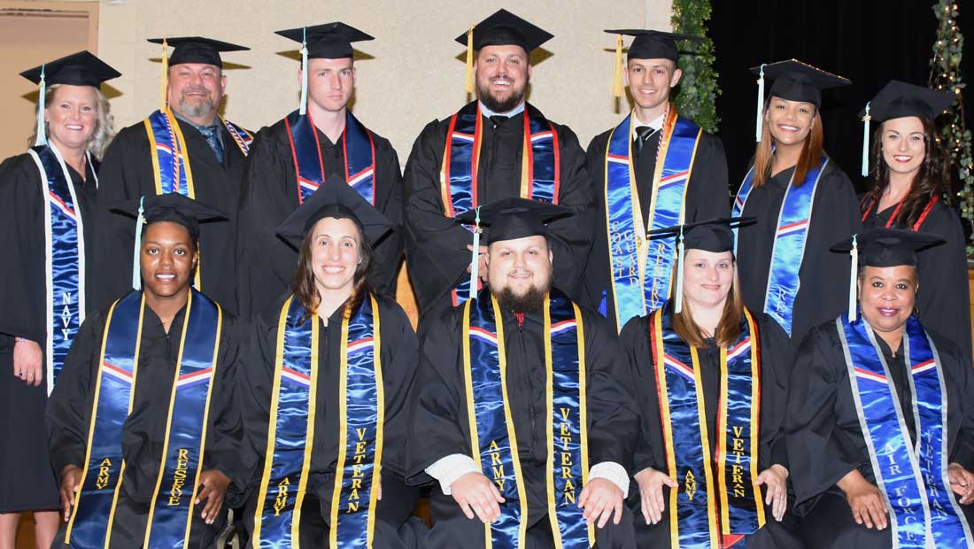 Successful graduates from different backgrounds pose at a commencement ceremony.