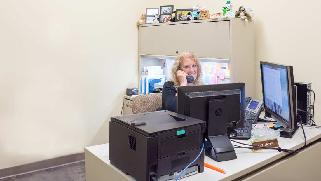 Woman sitting behind a desk on the phone