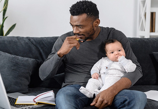 man sitting on couch holding a baby
